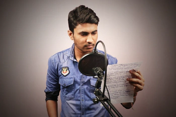 Indian man with script in front of microphone